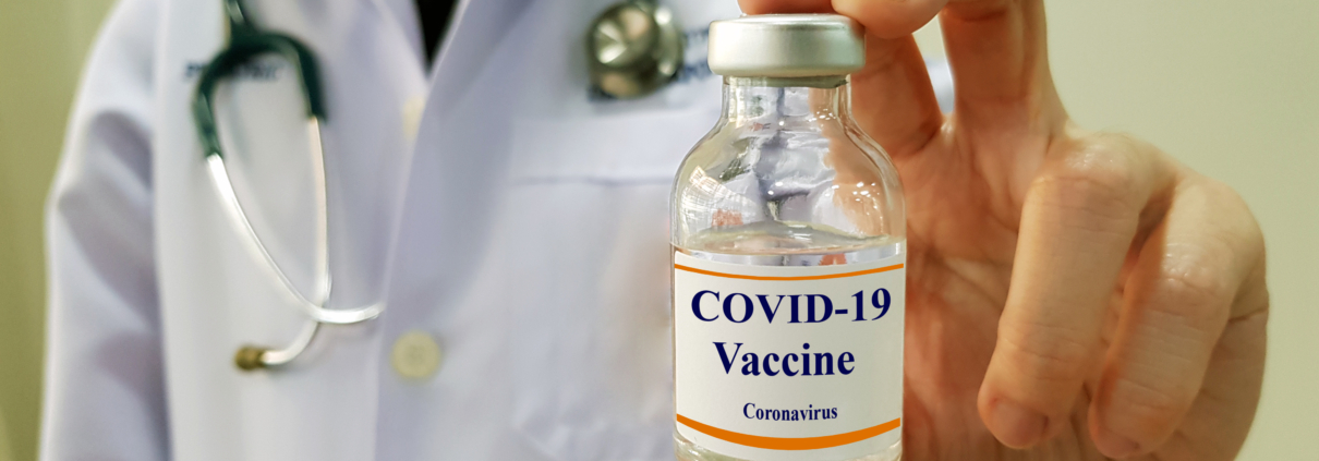 Image of person in labcoat holding a vaccine vial labeled COVID-19